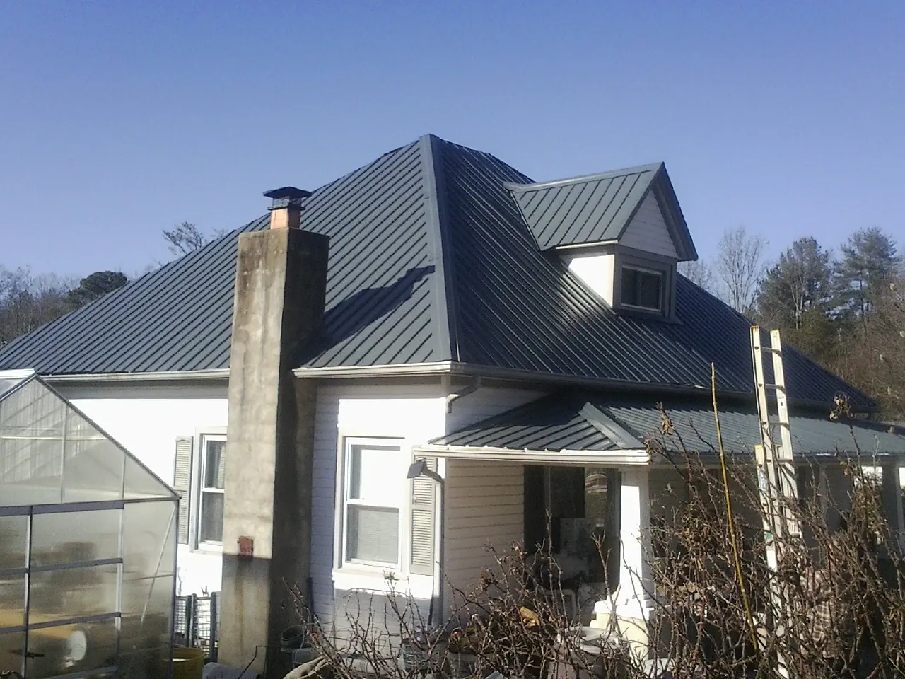Dark blue standing seam metal roof on a white farmhouse with dormer — Slate & Tile Roof Repair by Roofing Brothers in Aberdeen